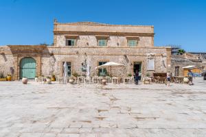 an old building with tables and umbrellas in a courtyard at Casamari nel centro di Marzamemi in Marzamemi