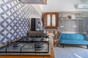 a kitchen with a stove and a blue couch at Casamari nel centro di Marzamemi in Marzamemi