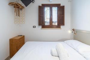 a bedroom with a white bed and a window at Casamari nel centro di Marzamemi in Marzamemi