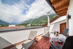 a balcony with a table and chairs and mountains at Sagschneiderhof Red Delicious in Plaus
