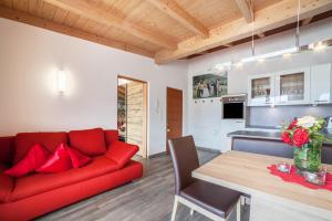 a living room with a red couch and a table at Sagschneiderhof Red Delicious in Plaus