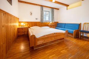 a bedroom with a large bed and a blue couch at Lindenhof Apt 6 in Vandoies