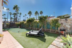 a garden with a bench on the grass with palm trees at Exclusive Villa with Heated Pool in Maspalomas