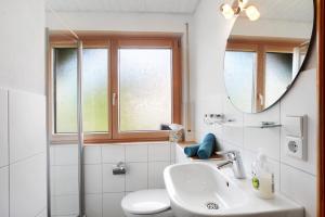 a white bathroom with a sink and a mirror at Gästehaus Hanni in Todtmoos