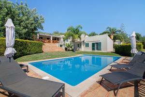 ein Schwimmbad mit Stühlen und ein Haus in der Unterkunft Excelente Studio in Loulé