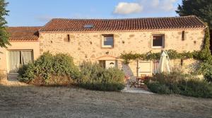 a large stone house with a table and an umbrella at La Grange De Vauviault in Bressuire