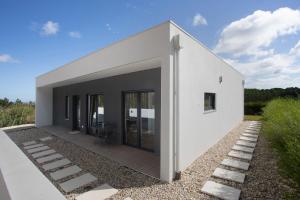 a white house with glass doors and a deck at Casa da Vinha in Óbidos