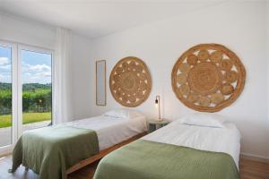 a white room with two beds and a window at Casa da Vinha in Óbidos