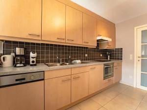 an empty kitchen with wooden cabinets and appliances at Apartment Zandloper with balcony by Interhome in Bredene
