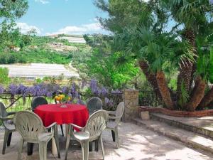 a table and chairs with a red table and trees at Le Mimose Bilo4 bis in Imperia
