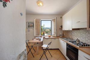 a kitchen with white cabinets and a table with chairs at Le Mimose Bilo4 bis in Imperia