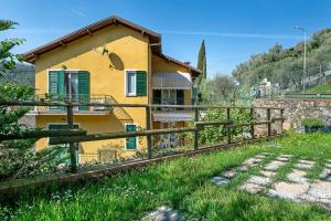 a yellow house with green shutters and a fence at Il Noce - vicino Chiavari in Leivi
