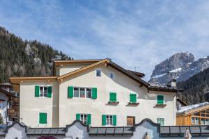 a building with green shutters on a mountain at Majon Baticher in Canazei