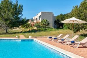 a swimming pool with lounge chairs and an umbrella at Can Roca in Illes Balears
