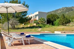 a pool with two chairs and an umbrella next to a pool at Can Roca in Illes Balears