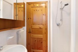 a bathroom with a wooden door next to a shower at Cima de' Piazzi Apartment 2 in Valdidentro