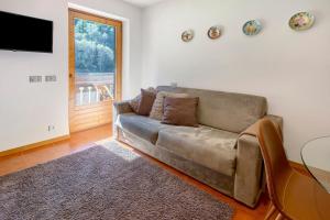 a living room with a brown couch and a window at Cima de' Piazzi Apartment 2 in Valdidentro