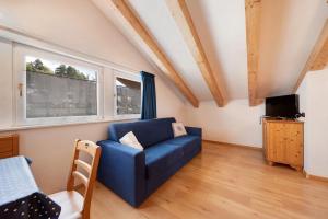 a living room with a blue couch and a tv at Residence Montebel Studio in Tesero