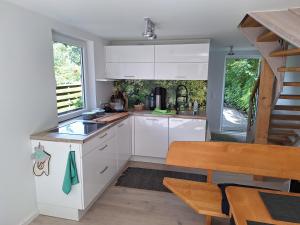 a kitchen with white cabinets and a wooden table at Ferienhaus am Wasser, Bootshaus in Güstrow