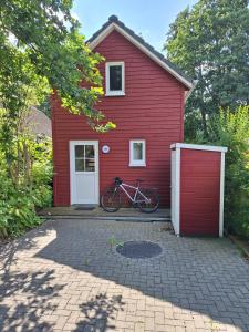 a red house with a bike parked in front of it at Ferienhaus am Wasser, Bootshaus in Güstrow
