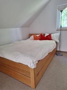 a bedroom with a bed with white sheets and red pillows at Ferienhaus am Wasser, Bootshaus in Güstrow