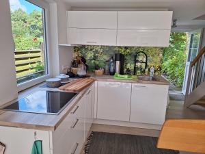 a kitchen with white cabinets and a large window at Ferienhaus am Wasser, Bootshaus in Güstrow +11 photos