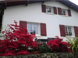 a white house with red flowers and windows at Villa Gastandeia in Cambo-les-Bains