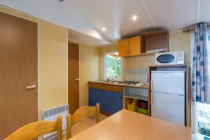 a small kitchen with a table and a refrigerator at Mobilhome La Clairière in Saint-Pompont