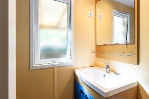 a bathroom with a sink and a window at Mobilhome La Clairière in Saint-Pompont +13 photos