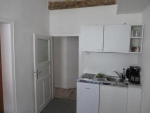 a kitchen with white cabinets and a sink and a door at Ferienwohnung Pfieffetalblick in Spangenberg