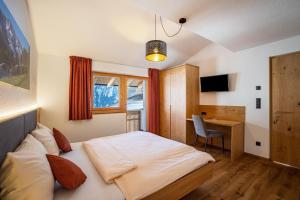a bedroom with a bed and a desk in it at App Hubertus - Wasserfallspitz in Sand in Taufers