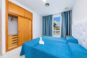 a bedroom with a blue bed and a large window at Apartamento Via Alemanya in Can Picafort +17 photos