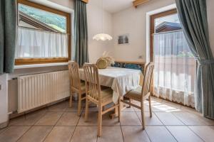 a dining room with a table and chairs and windows at App Sonne Nr 18 in Lutago