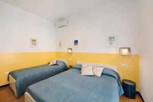 two beds in a bedroom with yellow and white walls at Il ciliegio di Miki in Genoa