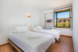 two beds in a room with a window at Ran de Mar in Son Serra de Marina