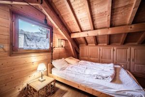 a bed in a wooden room with a window at Chalet 6p Confort - Le bouvreuil in Verchaix
