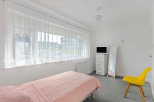 a white bedroom with a bed and a yellow chair at Stainorstarve in London