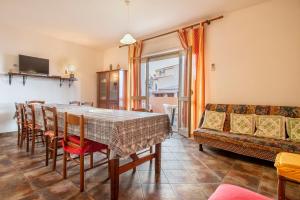 a dining room with a table and chairs and a couch at Veranda Vista Mare Isola Rossa in Isola Rossa