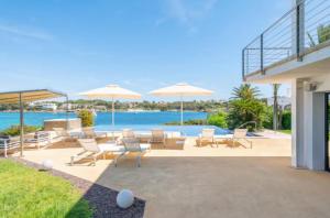 a patio with chairs and umbrellas and a pool at Sa Bateria in Portocolom