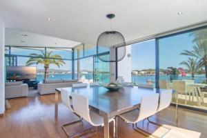 a dining room with a glass table and white chairs at Sa Bateria in Portocolom
