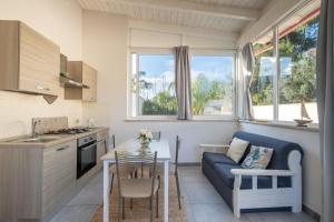 a kitchen and living room with a blue couch and a table at Elenya Garden Retreat in Torre Lapillo