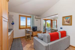 a living room with a gray couch and a kitchen at 4 Appartamento Cala Brandinchi in San Teodoro