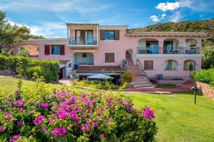 a large pink house with flowers in the yard at 4 Appartamento Cala Brandinchi in San Teodoro