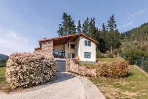 a small white house with a garage at La Riega Del Peral in Ojedo