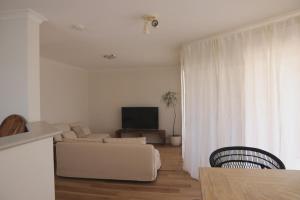 a white living room with a couch and a tv at Kawa House in Kalbarri