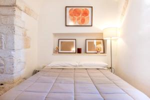 a bed in a white room with two mirrors at Dimora La Piana in Ostuni