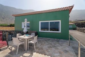 a green house with a table and chairs on a patio at Casa Elvira in Frontera