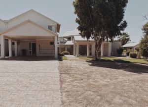 a house with a tree in front of a driveway at Kawa House in Kalbarri