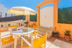 a patio with a white table and chairs and an umbrella at Villa Lidia in Cala Galdana