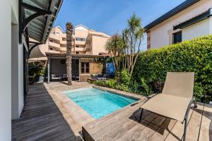 a patio with a swimming pool and two chairs at La Villa Sanson in Arcachon